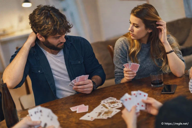Jeunes adultes jouant aux cartes autour d'une table